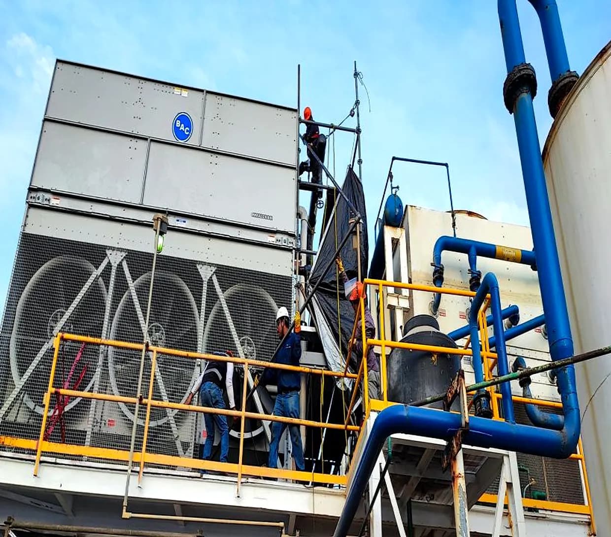 Cuadrilla con casco y arnés trabajando sobre una torre de enfriamiento